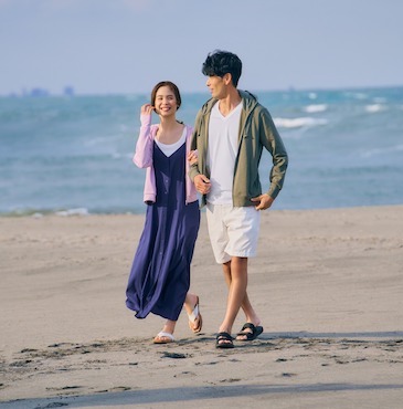Young couple strolls along the beach in Uniqlo fashions