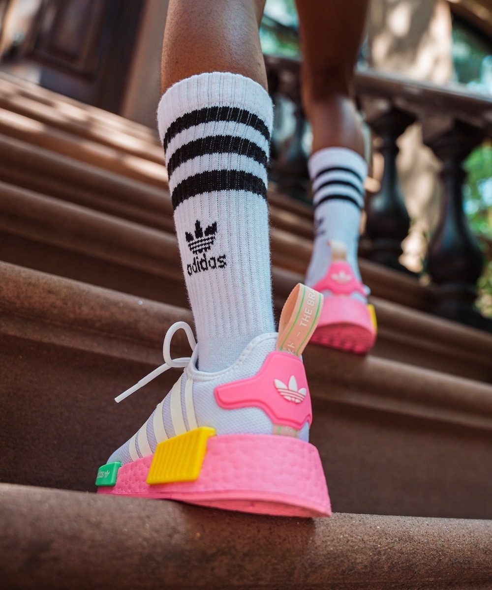 Person in black and white socks and bright pink shoes from Foot Locker