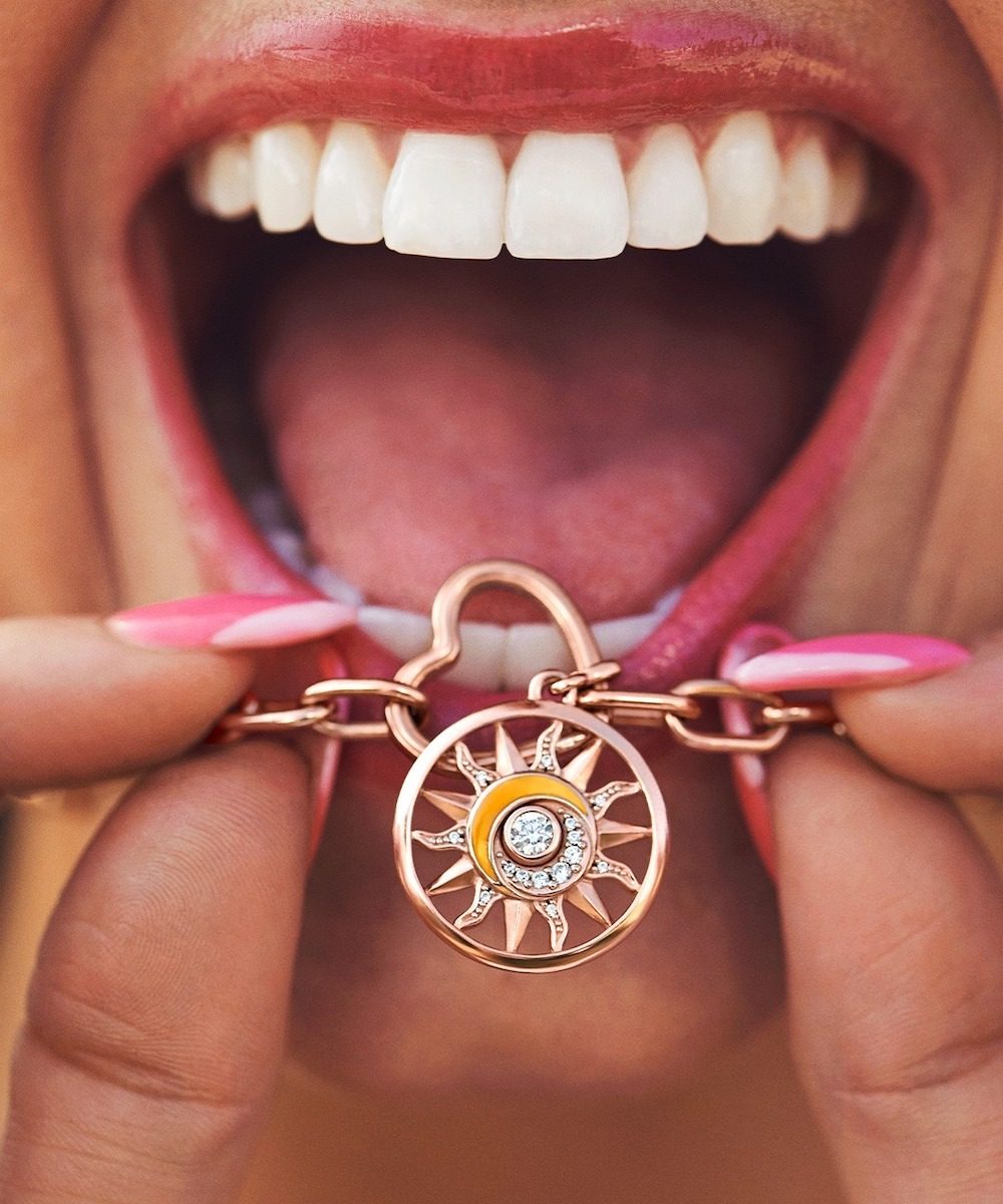 Woman in pink lipstick shows off sunburst Pandora necklace