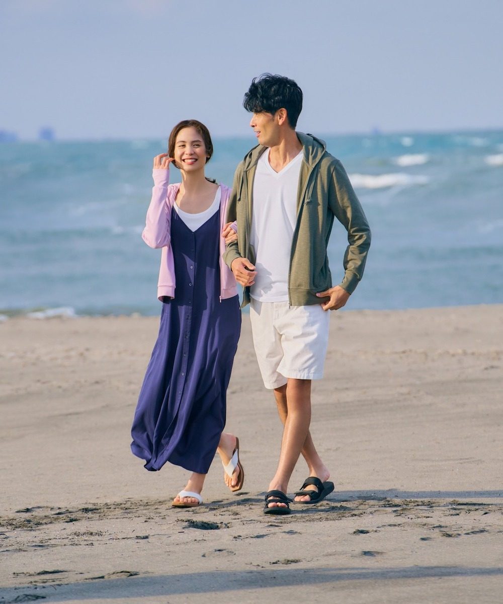 Young couple strolls along the beach in Uniqlo fashions
