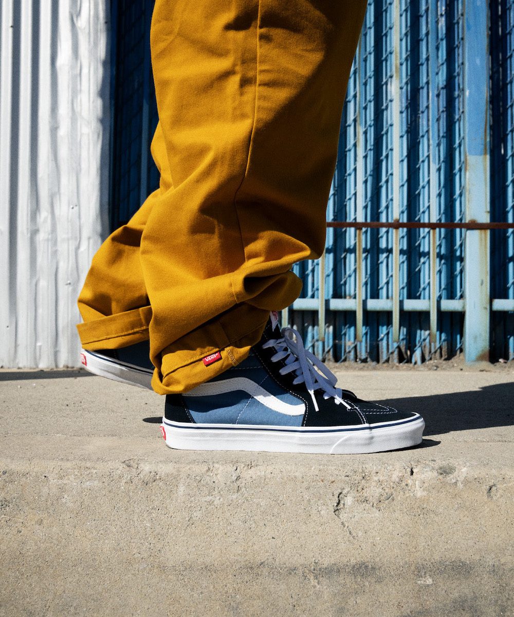 Person wearing gold pants and blue classic Vans shoes